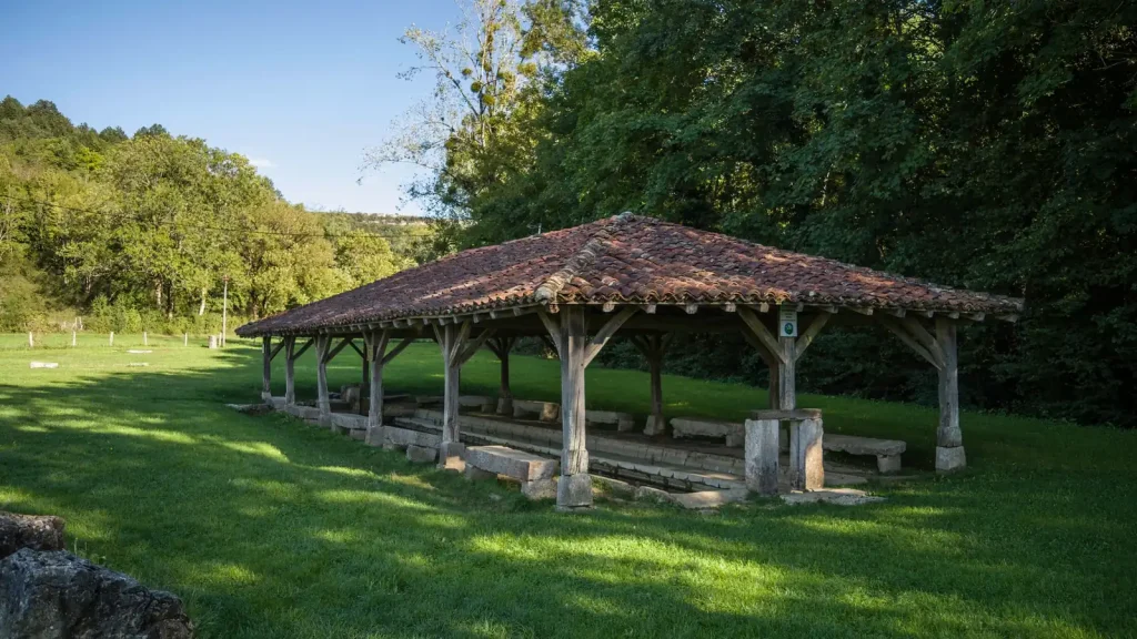 Un ancien lavoir couvert au milieu de la verdure d'un village de l'Ain