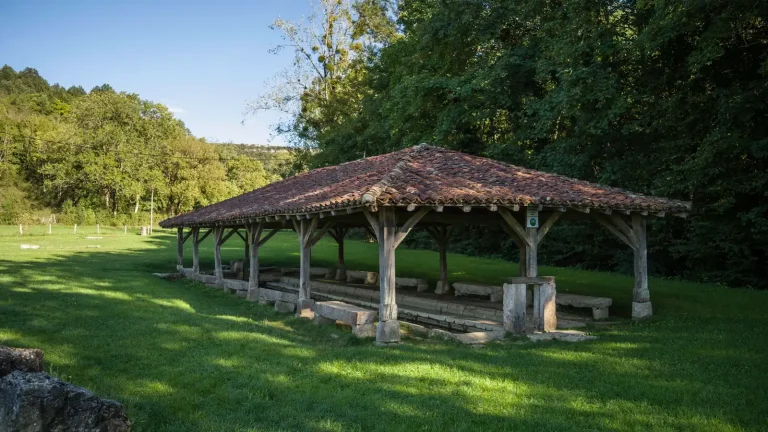 Un ancien lavoir couvert au milieu de la verdure d'un village de l'Ain