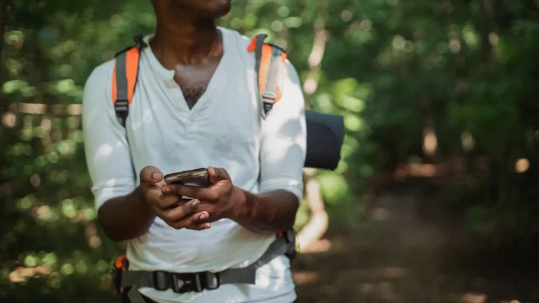 Un randonneur tient son smartphone en forêt pour suivre son itinéraire