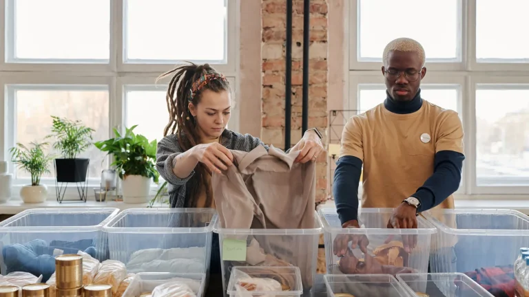 Deux bénévoles trient des vêtements et des denrées dans des bacs transparents