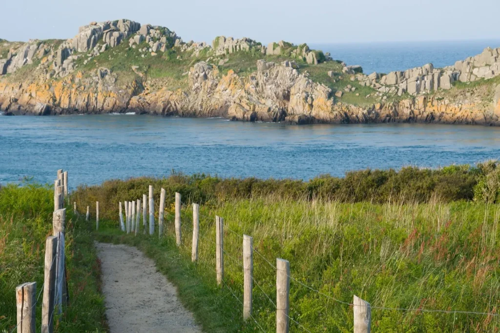 Sentier côtier bordé de piquets au-dessus de la mer, en Bretagne